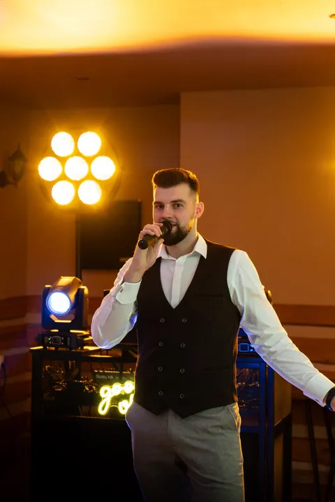 Wodzirej z mikrofonem w bursztynowym świetle
